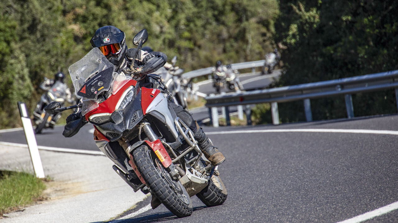 Motorradgruppe in einer Kurve, vorn eine rote Reiseenduro
